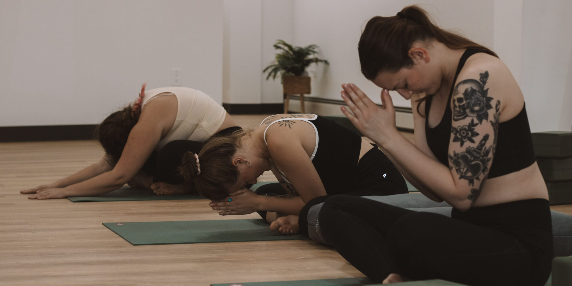 Three yoga students concluding their practice with breathwork.